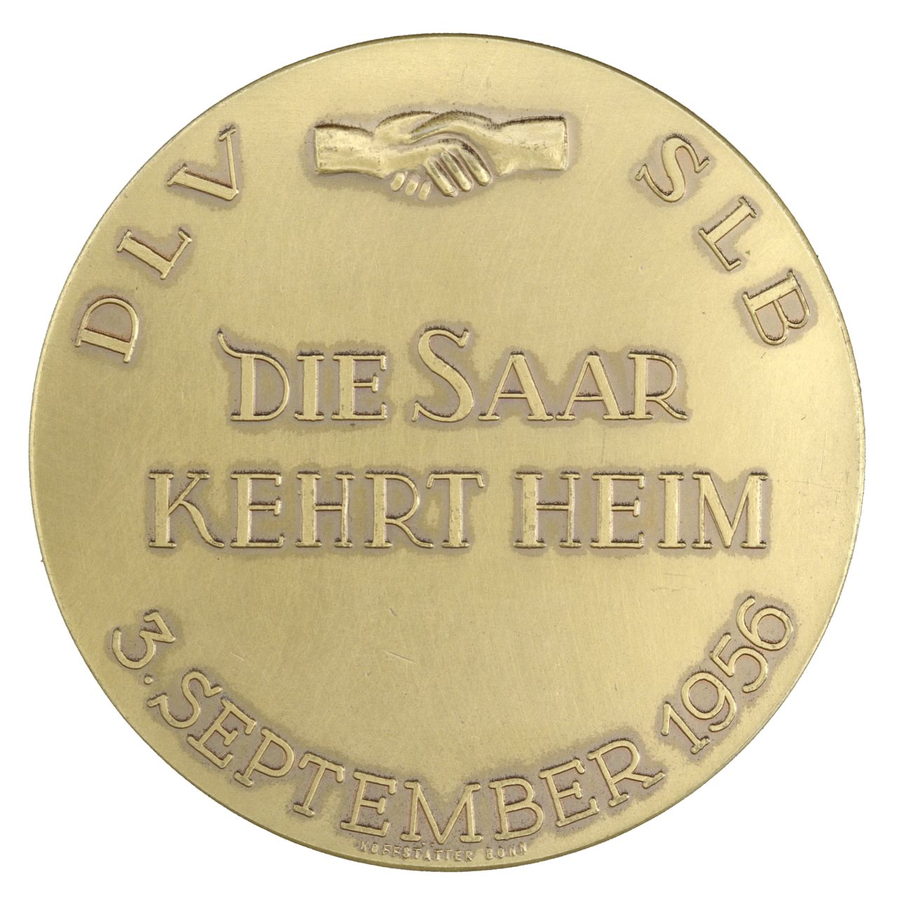 Auf der messingfarbenen Medaillen-Vorderseite erhabene Umschrift 'DLV SLB 3. September 1956'. Zwischen DLV und SLB zwei schüttelnde Hände. In der Mitte erhaben in Großbuchstaben 'Die Saar kehrt heim'.