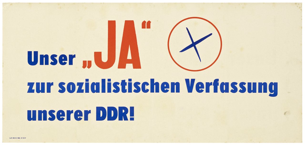 Blaue und rote Schrift auf gelblichem Papier: Unser JA zur sozialistischen Verfassung unserer DDR! Neben dem JA ein angekreuzter Kreis.