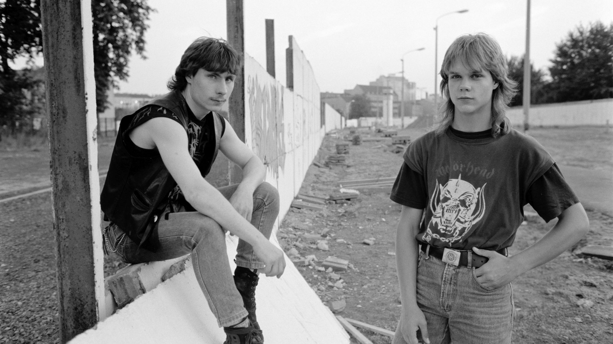 Two teenagers pose at a former border section in Berlin.