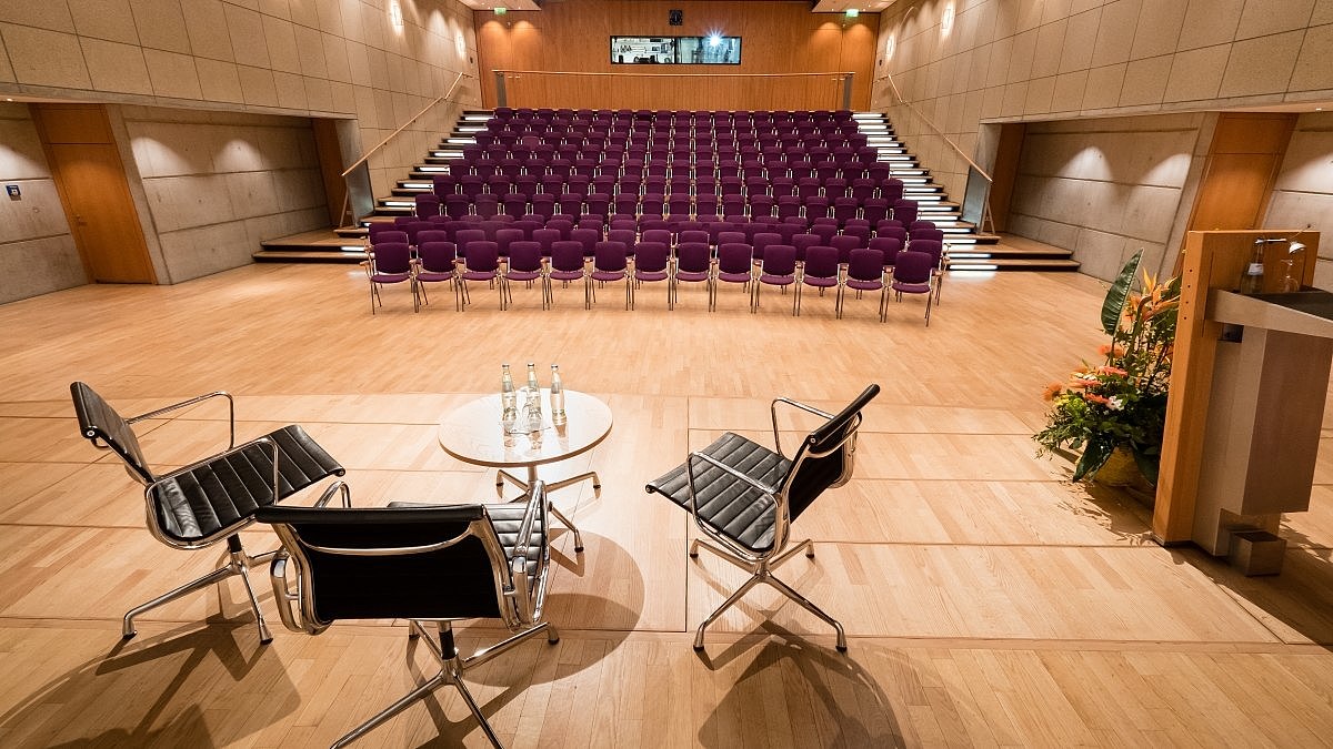 Blick von einer Bühne in einen großen Raum mit aufsteigenden Stuhlreihen.