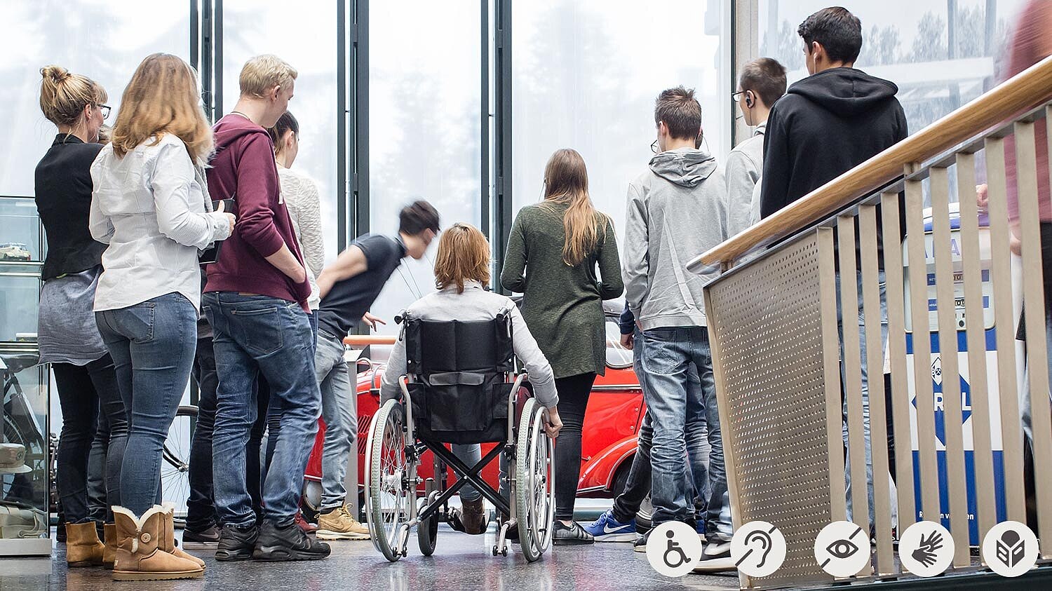 A group with a girl in a wheelchair during a guided tour through Haus der Geschichte museum.