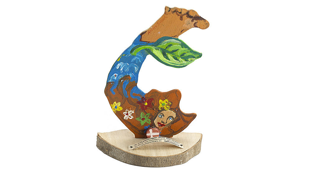 Beidseitig handbemalte Abbildung einer Meerjungfrau auf einer Baumscheibe, davor der Text: 'In CO²penhagen muss was laufen/für Klima- und Urwaldschutz zur UN-Konferenz'.