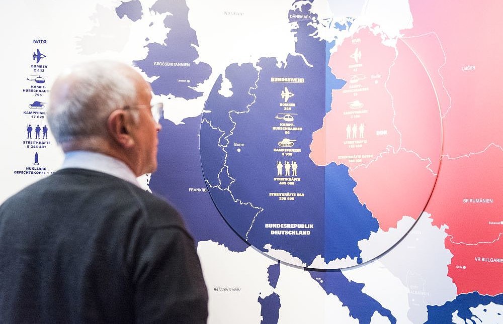 Ein Mann steht vor einer Europakarte, in der die UdSSR rot, die europäischen Staaten westlich davon blau eingefärbt sind