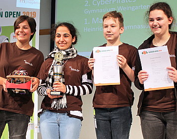 vier Schülerinnen und Schüler mit Pokal und Urkunden bei einer Siegerehrung