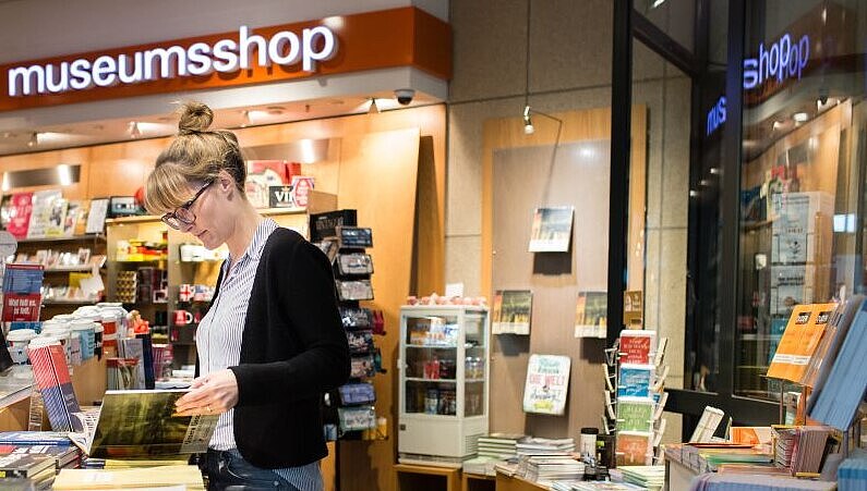 Eine Frau blättert im Buch zur Dauerausstellung im Museumsshop