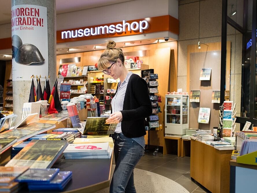 Eine Frau blättert im Buch zur Dauerausstellung im Museumsshop