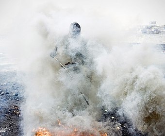 Foto von der Verbrennung der Kunststoffummantelung von Kabeln in Accra, Ghana 2011. Zu sehen ist eine große Rauchwolke und die Umrisse eines Menschen