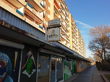 Plattenbau mit Schild "Zur Kleinen Kneipe"