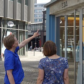 Zwei Frauen stehen vor dem Tränenpalast, im Hintergrund ist der Bahnhof Friedrichstraße zu sehen.