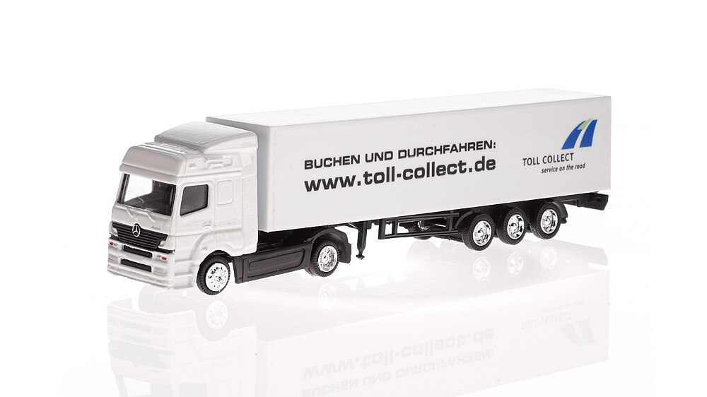 Weißer Mercedes-LKW mit schwarzer Aufschrift: "Buchen und Durchfahren: / www.toll-collect.de",  blau-grünem Symbol mit der Schrift: "Toll collect / service on the road".