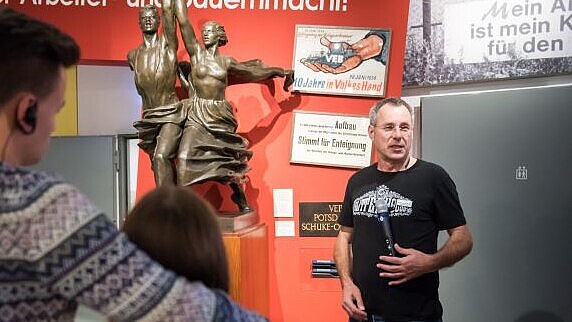 Ein Gruppenbegleiter spricht zu Besuchern in der Dauerausstellung