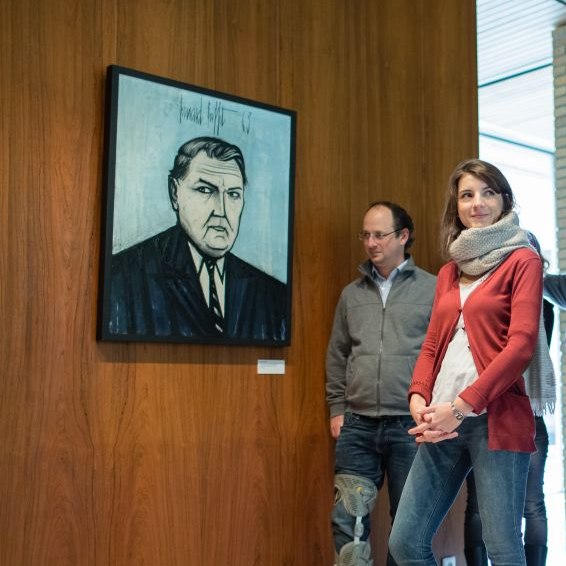 Besucherin und Besucher vor einem Porträt Ludwig Erhards