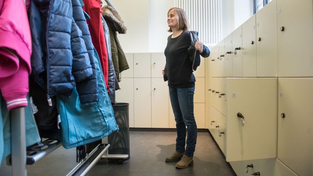 Eine Frau zieht eine Jacke in der Garderobe an