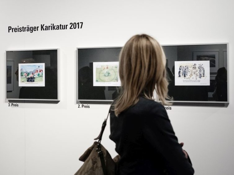 A visitor looks at the award winners in the category caricature