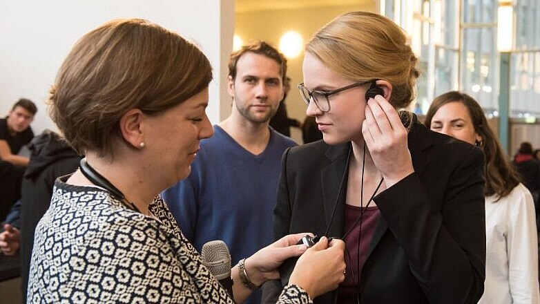 A young woman is holding her earphone before a guided visit