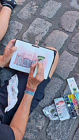 Foto Person beim Malen eines Aquarellbildes und Farbkasten