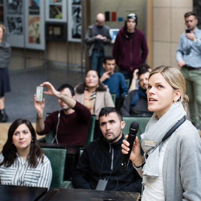 Eine Gruppenbegleiterin spricht zu Besuchern im Bundestagsgestühl