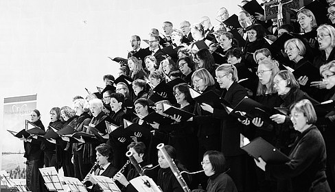 schwarz-weißes Foto von einem singenden Chor, fotografiert von der Seite.