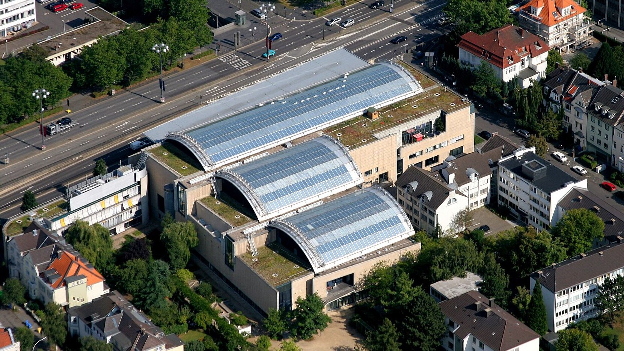 Vogelperspektive auf das Haus der Geschichte in Bonn, man sieht die drei Bögen des Glasdaches