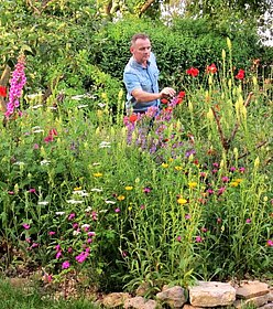Daniel Jakumeit im Garten, umgeben von blühenden Stauden
