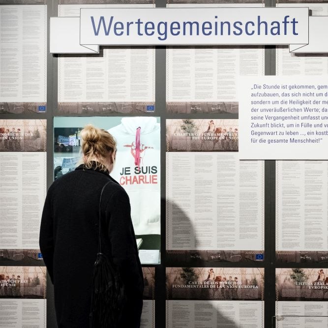 Besucherin vor einer Wand mit der Charta der Grundrechte der europäischen Union in allen Sprachen der EU