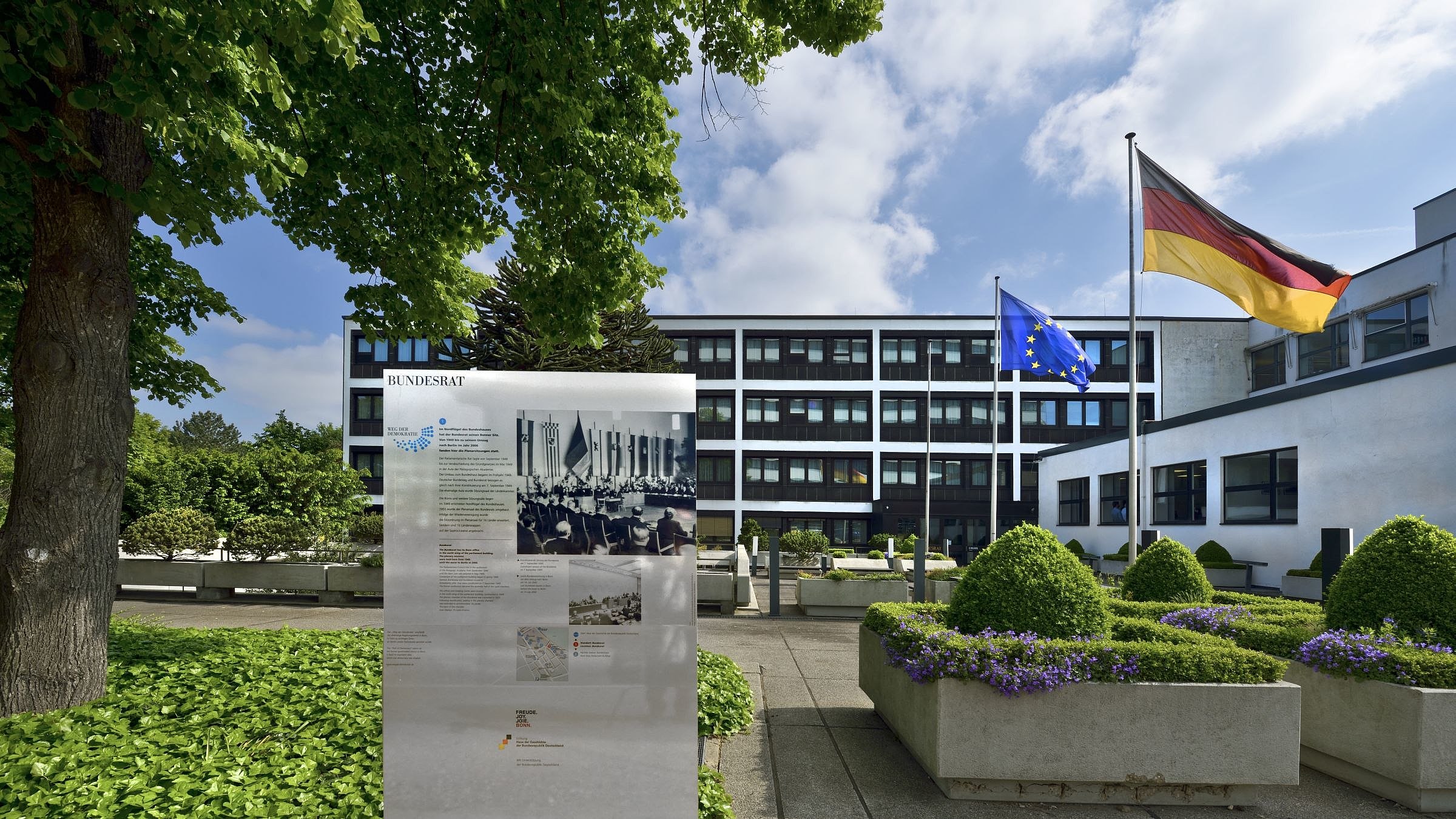 Blick auf den Nordflügel des Bundeshauses Bonn. Im Vordergrund die Tafel mit den Informationen zum Weg der Demokratie
