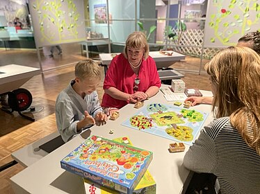 Eine Gruppe spielt am Spieletisch der Wechselausstellung