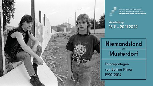 Zwei junge Männer an der teils abgerissenen Berliner Mauer