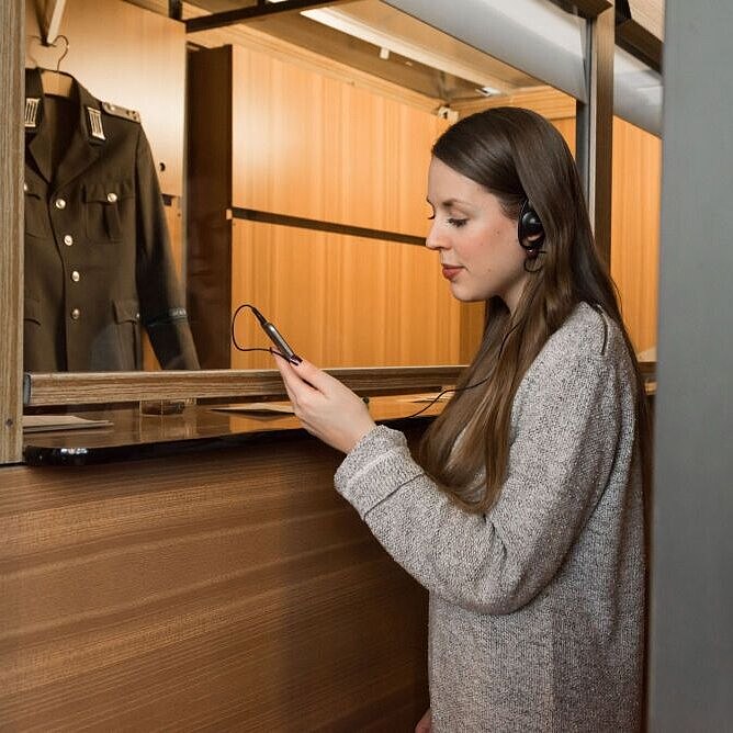 A young woman is using the audio guide to the Palace of Tears.