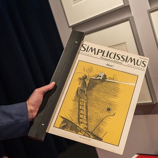 Eine Hand hält eine Ausgabe der Satire-Zeitschrift Simplicissimus