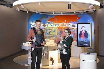 Zwei Eltern mit Babys in der Trage in der Dauerausstellung