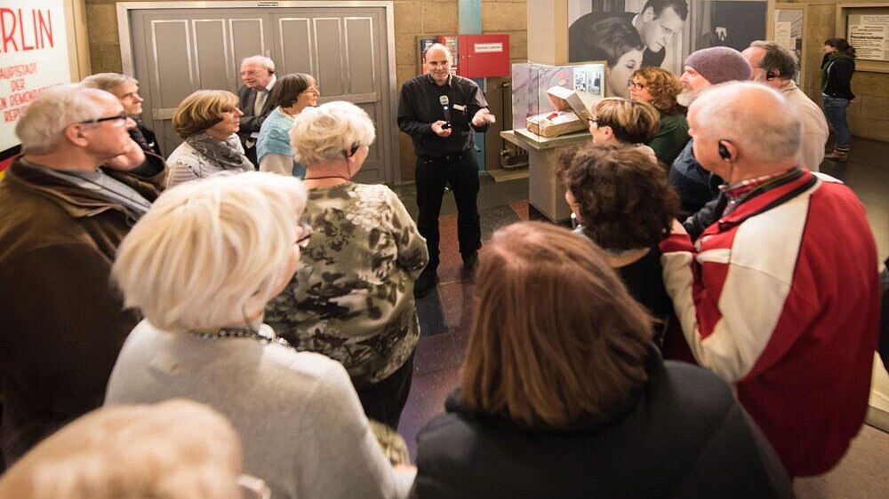 A group of elderly visitors is attending a guided visit