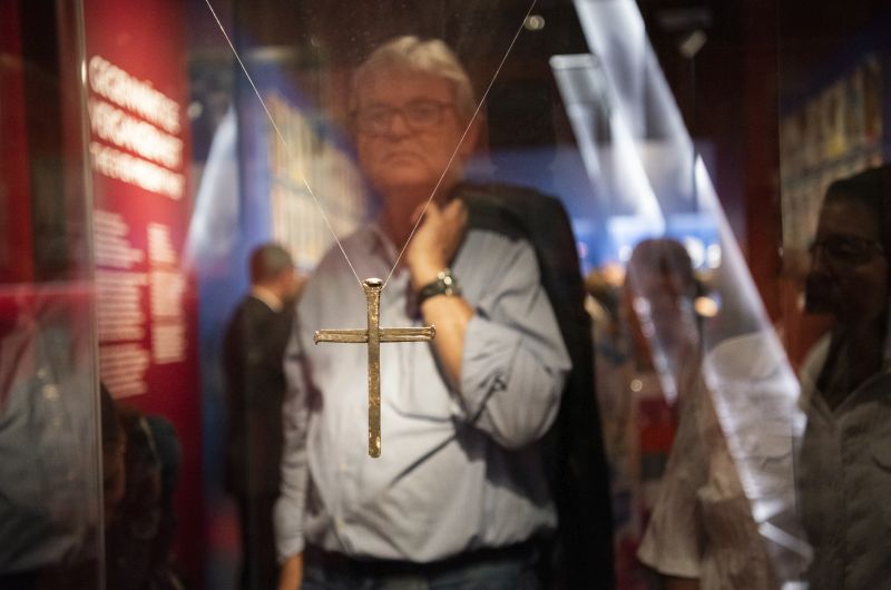 A visitor is standing behind a display case where the "Cross of Nails" form COventry is hanging.