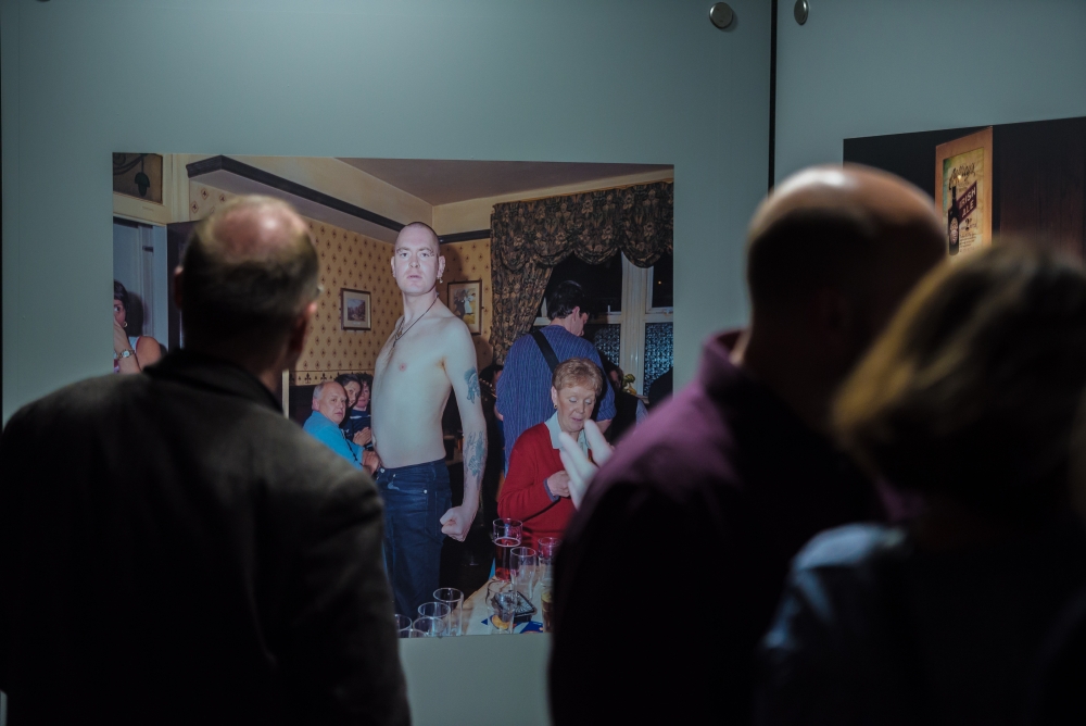 Besucherinnen und Besucher vor einer Fotografie von Peter Dench.