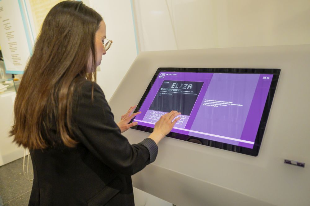 Eine Besucherin schreibt auf einem Touchscreen mit dem Chatbot "Eliza" an einer interaktiven Station der Ausstellung.