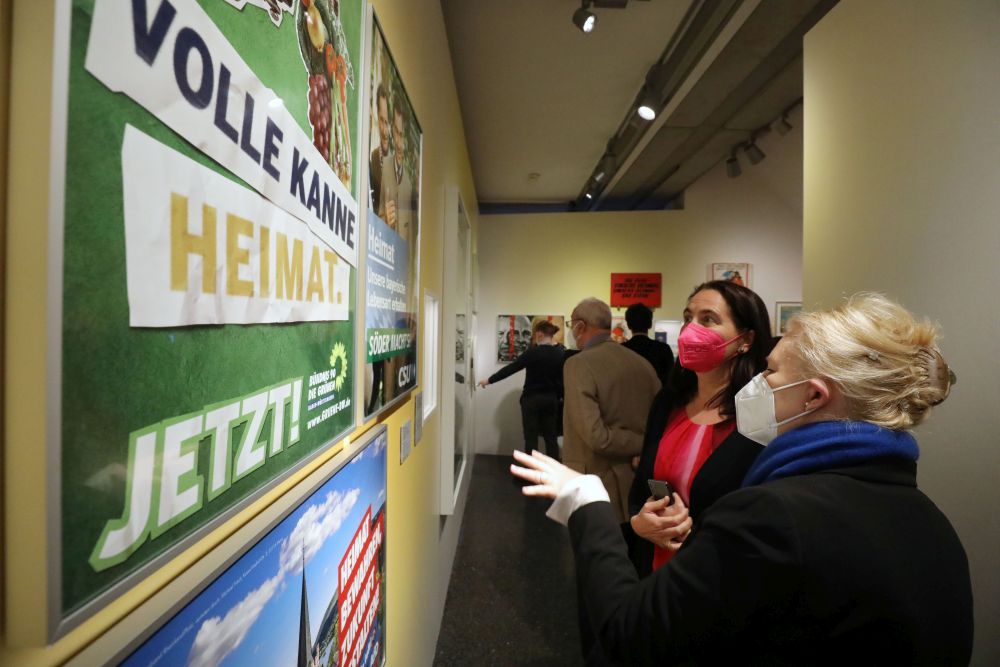 Zwei Frauen stehen vor einer Ausstellungswand mit Wahlplakaten.
