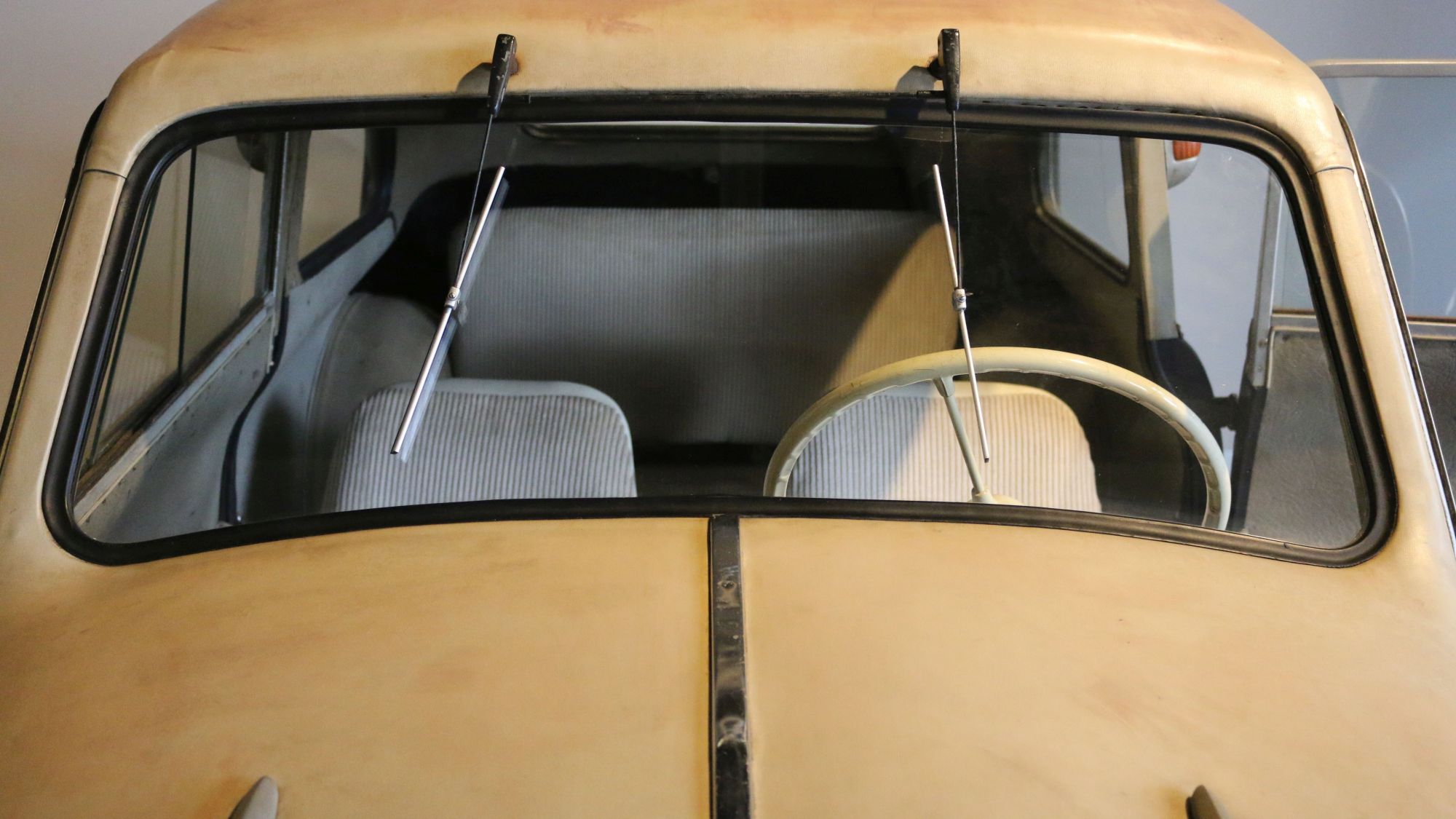 Blick in das Innere des "Leukoplastbombers" Lloyd 300 Blick über die beige Motorhaube eines Kleinwagens in das graubezogene Innere des Autos.