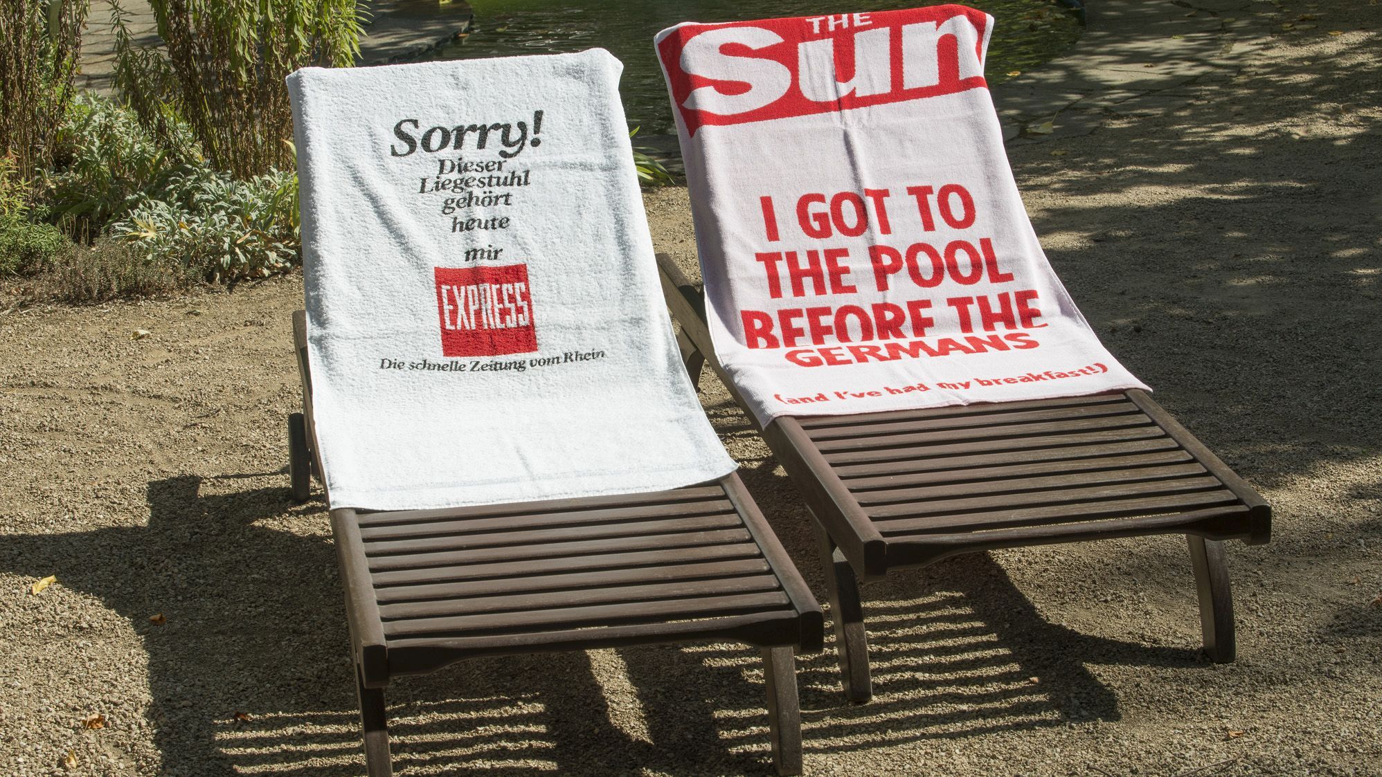 Zwei Liegestühle mit Handtüchern, eines vom Express, "Sorry, dieser LIegestuhl gehört heute mir!" und eines von der britischen Boulevardzeitung "The Sun", "I got to the pool before the Germans".