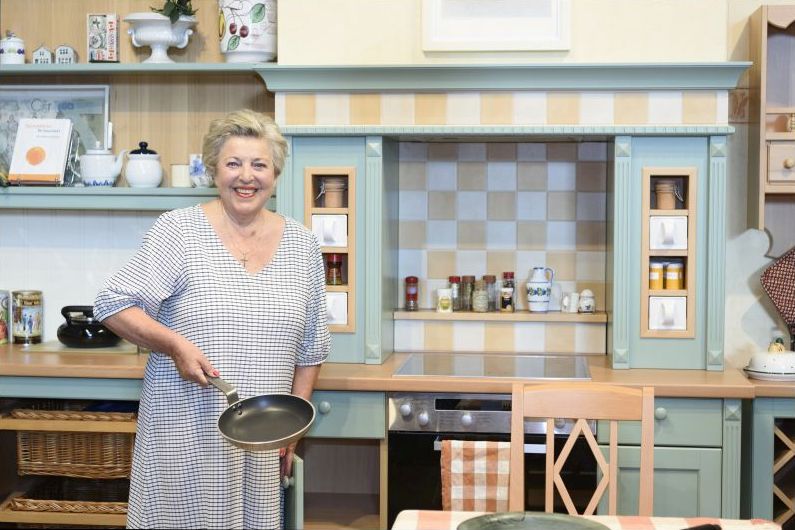 Schauspielerin Marie-Luise Marjan steht mit einer Bratpfanne in der Hand in einer Küche-Kulisse