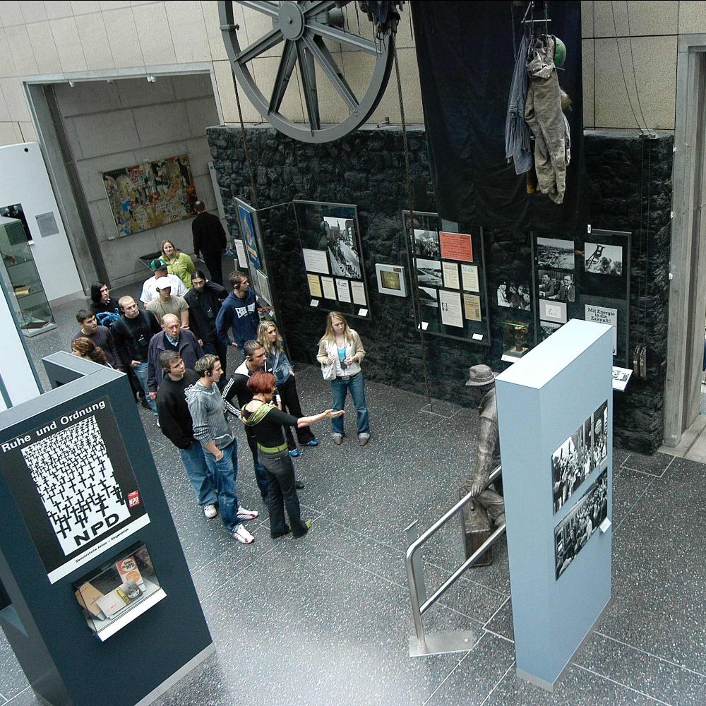 Blick von oben auf eine Gruppe von Besucherinnen und Besucher in der Dauerausstellung.