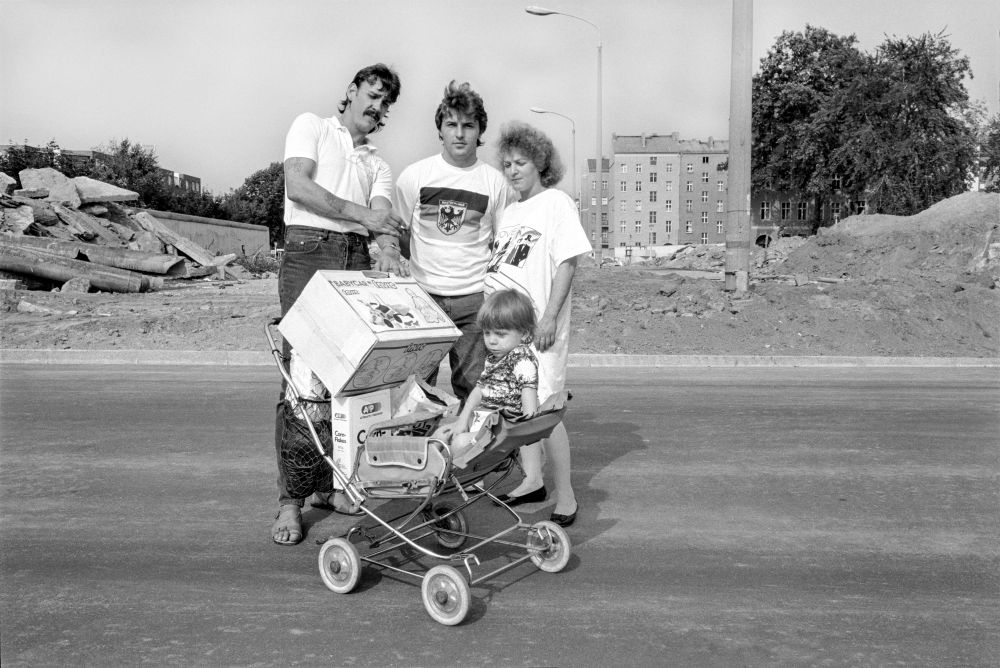 Eine Personengruppe bzw. Familie mit Kinderwagen steht vor einer Baustelle