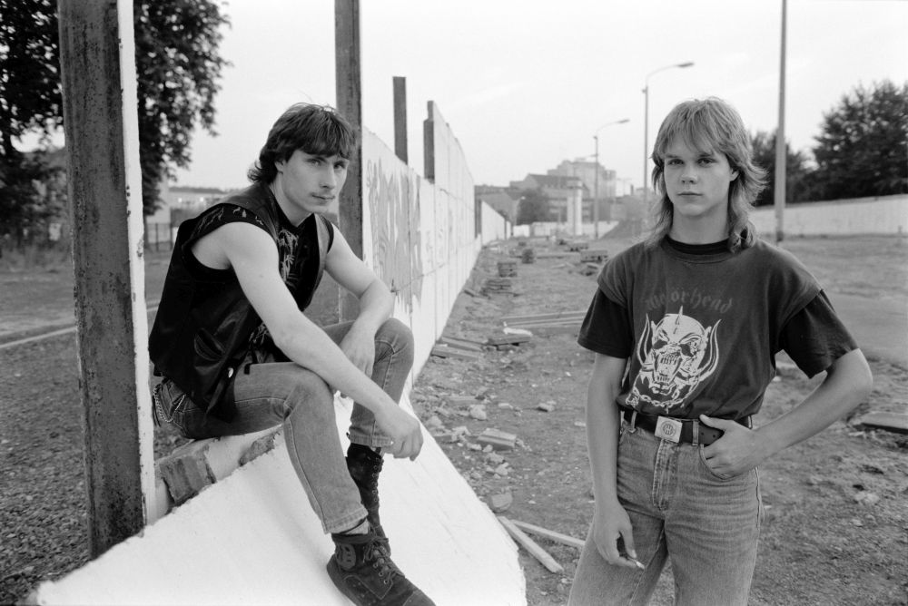 Zwei Jugendliche posieren bei einem ehemaligen Grenzabschnitt in Berlin.