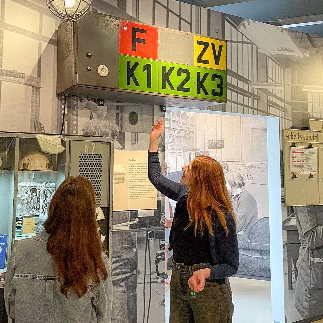 Eine Begleiterin zeigt einer Besucherin ein Objekt in der Ausstellung