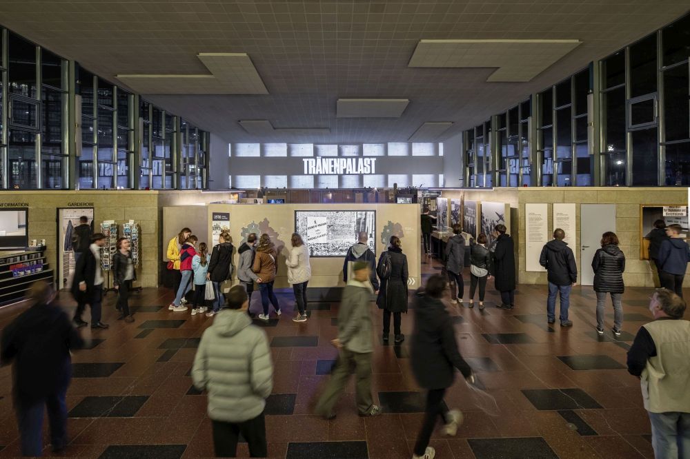 Besucherinnen und Besucher zum Festival of Lights im Tränenpalast. Im Hintergrund: Projektion mit Text Tränenpalast an der Wand.