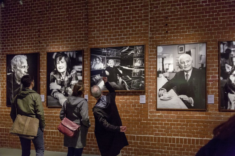 Besucher vor einer Wand mit Fotos