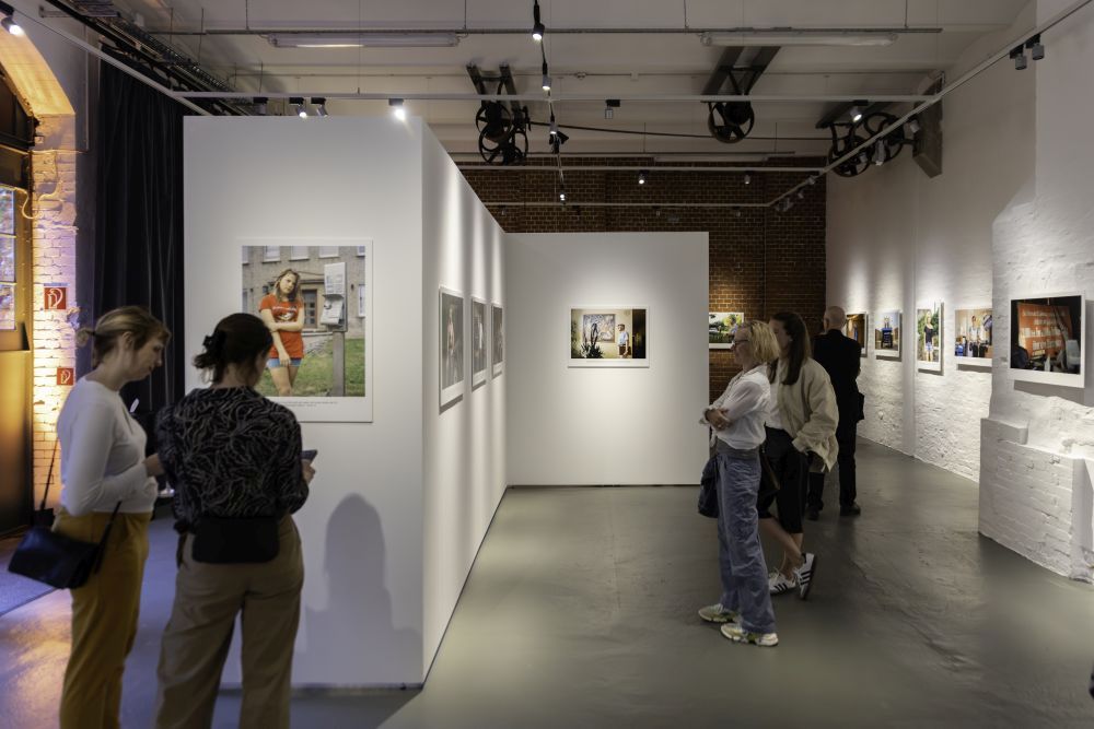 Besucherinnen und Besucher betrachten Farbfotografien der Mestlin-Reportage in der Ausstellung