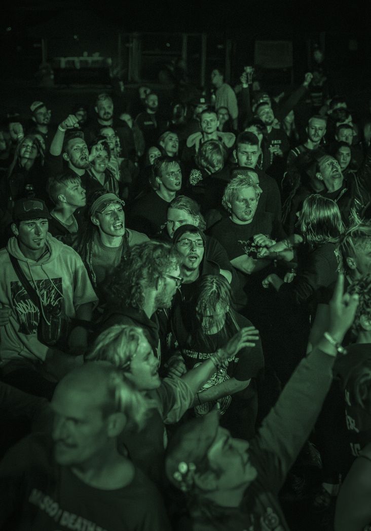 Das Publikum bei einem Konzert. Die Zuschauenden sind in grünlichem Licht. 