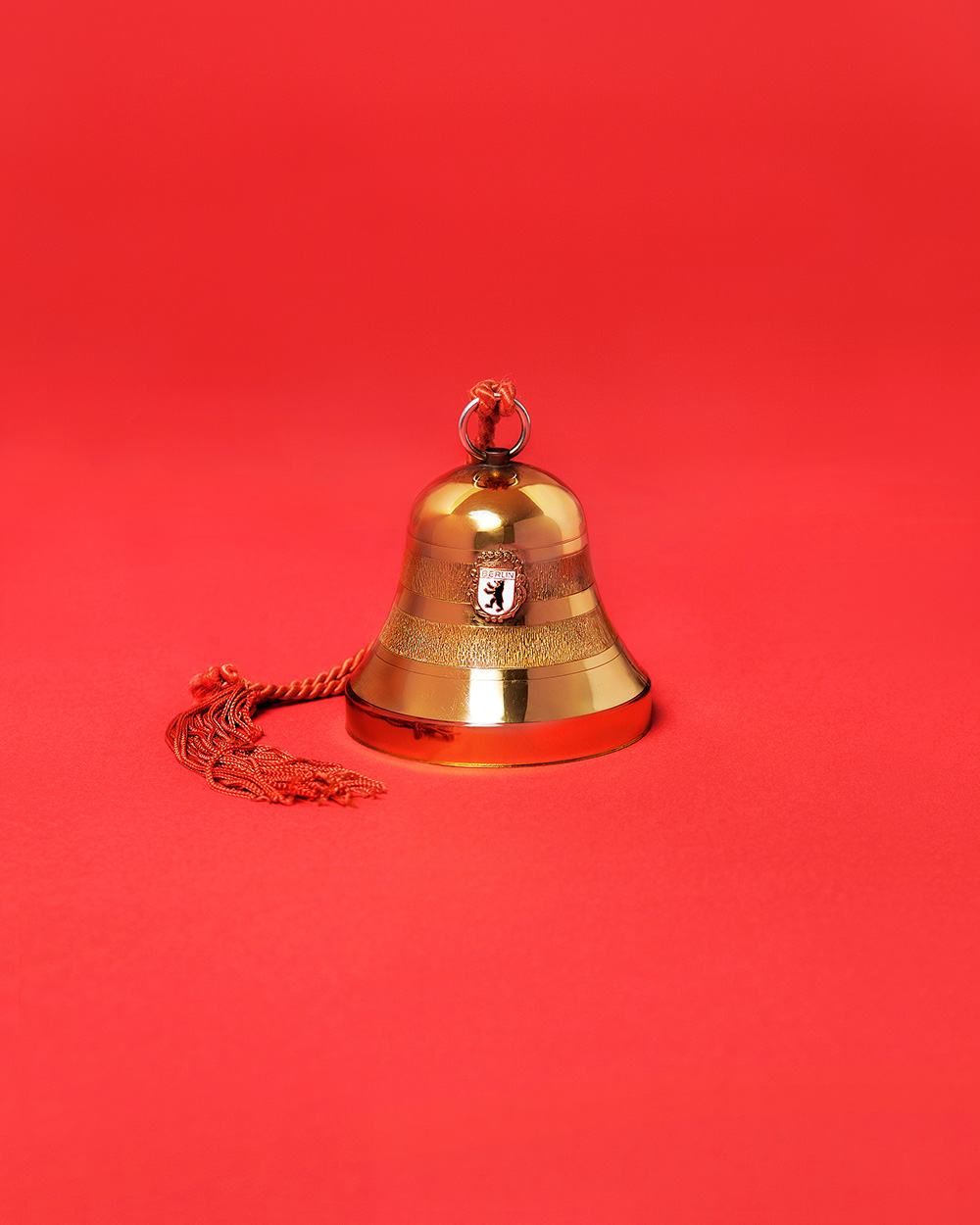 Music box in the shape of a bell. Gold. Coat of arms with inscription Berlin on red background.