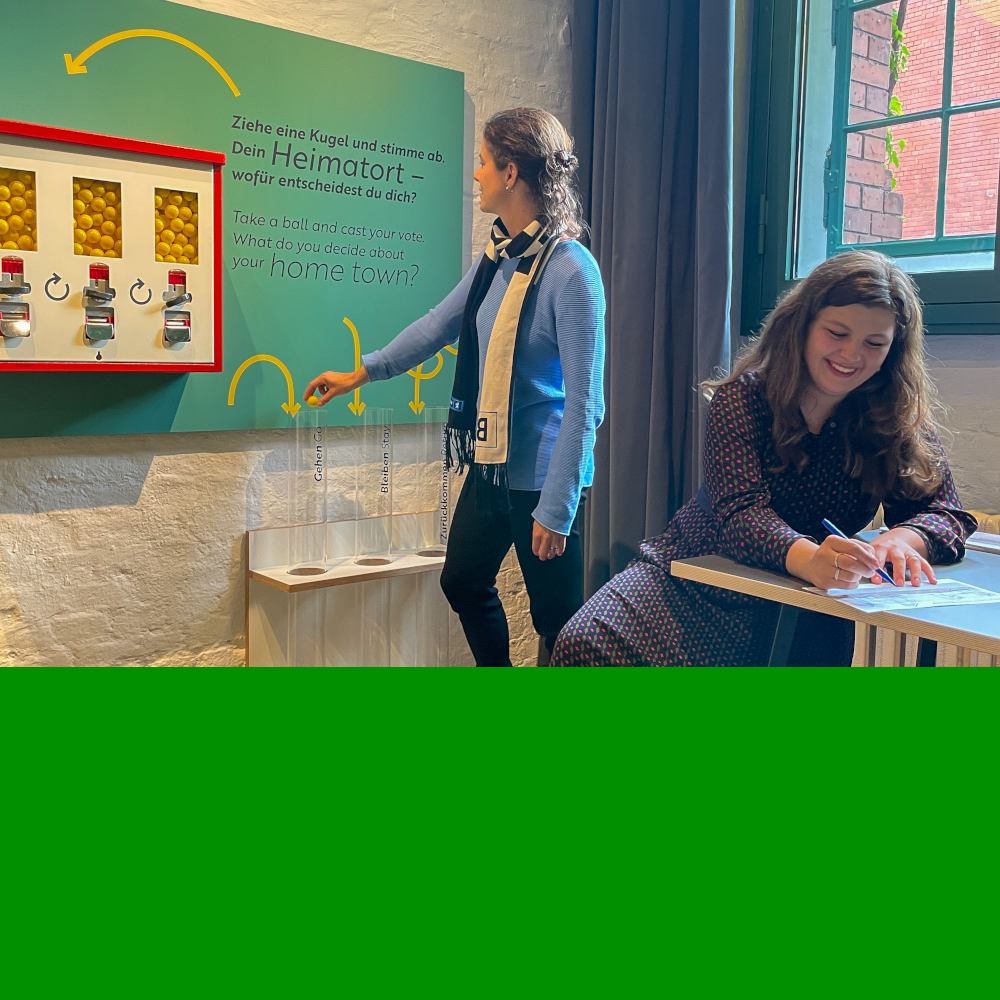 Zwei Besucherinnen gestalten die Ausstellung an einem Tisch in der Ausstellung mit.