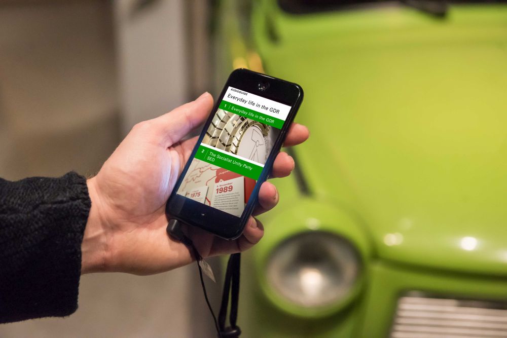 Hand with smartphone, on the display you can see the AudioGuide for the permanent exhibition 'Everyday Life in the GDR' in the Museum in der Kulturbrauerei